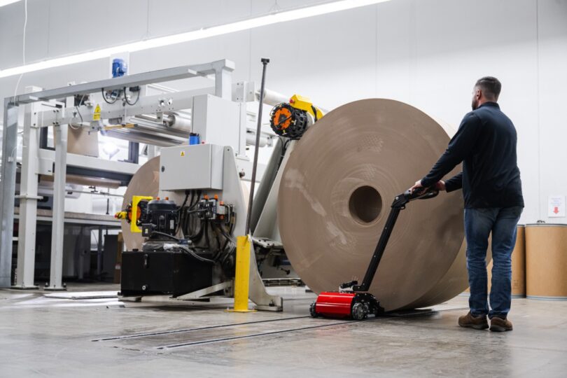 PowerPusher moving a paper roll near a converting line, replacing forklift use in tight production spaces